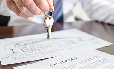 real estate attorney handing keys over a contract lying on a desk